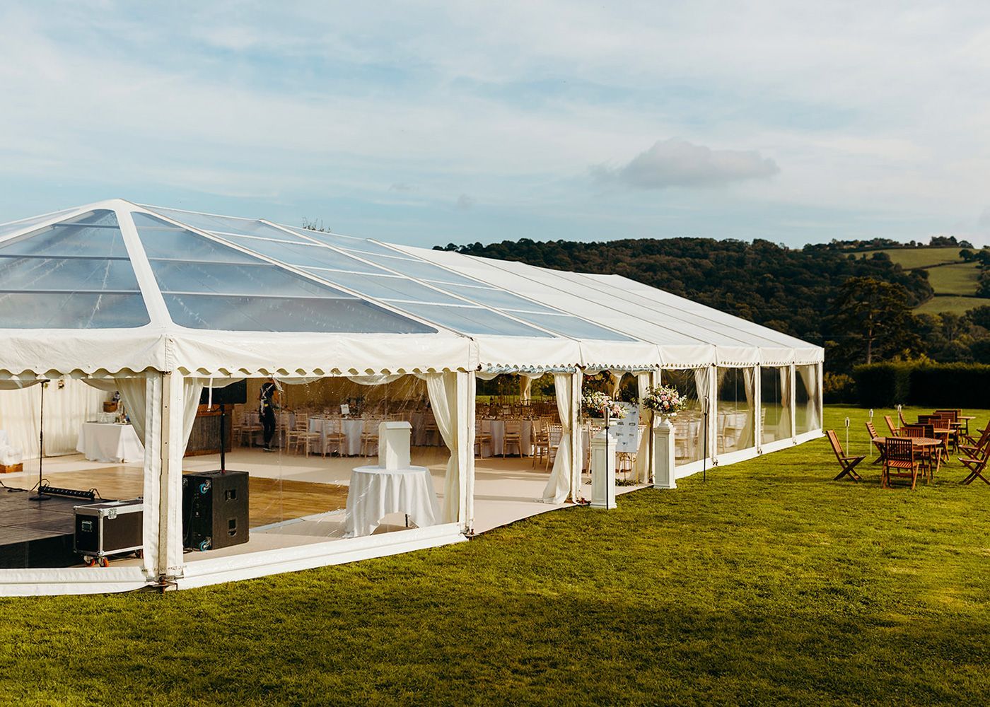 A large clear tent is sitting in the middle of a grassy field.