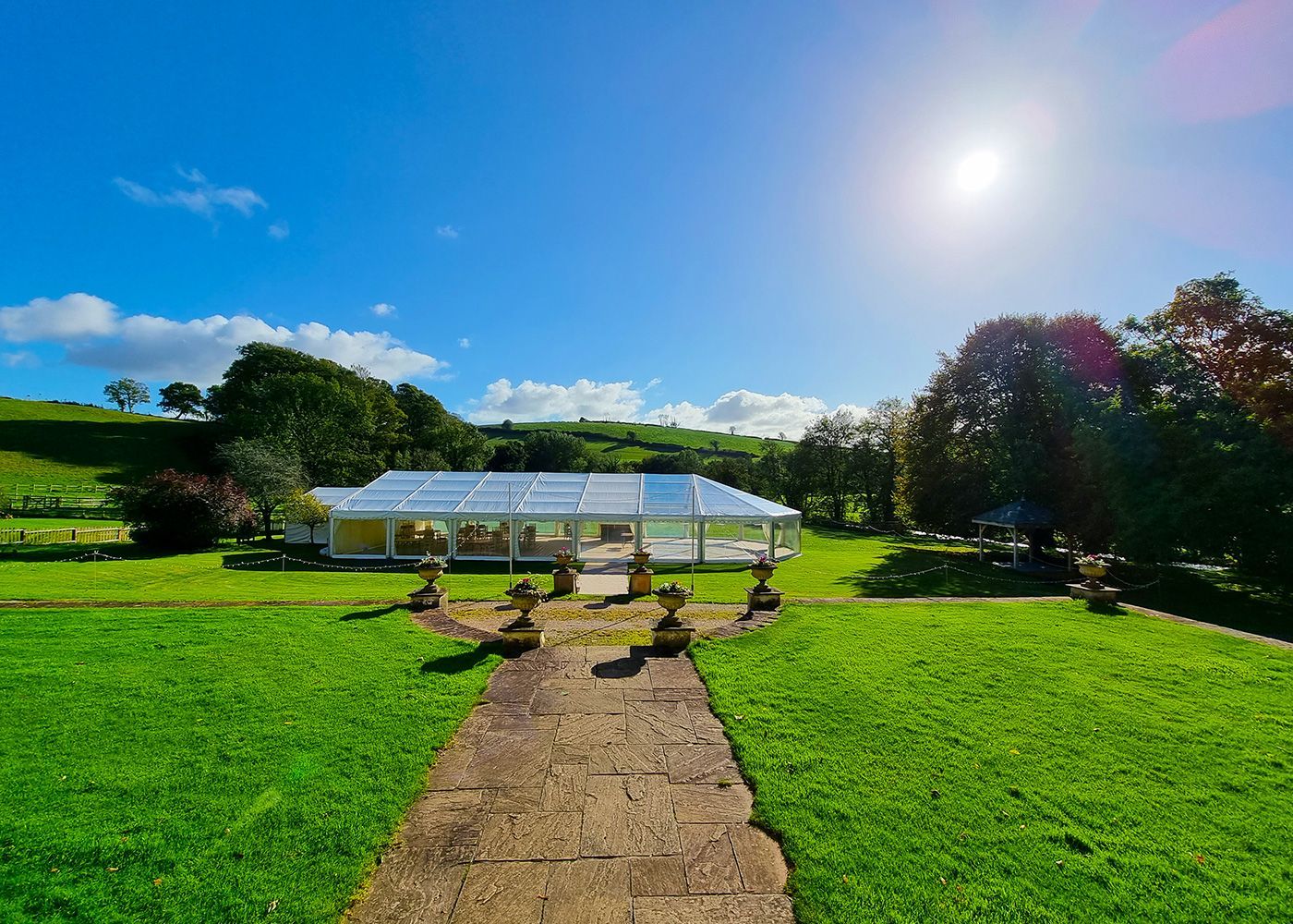 A clear tent is sitting in the middle of a lush green field.