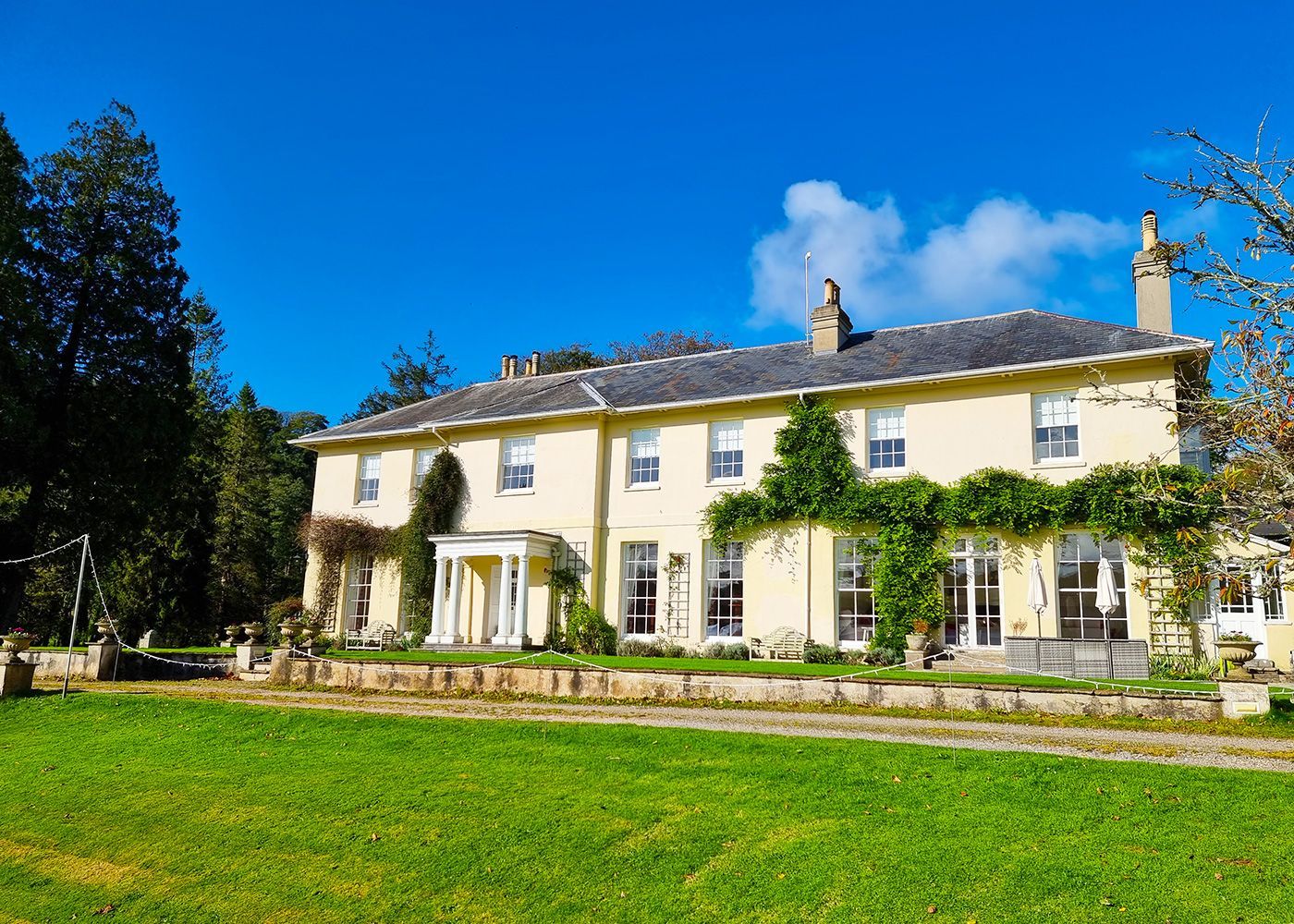 A large white house with a lush green lawn in front of it.
