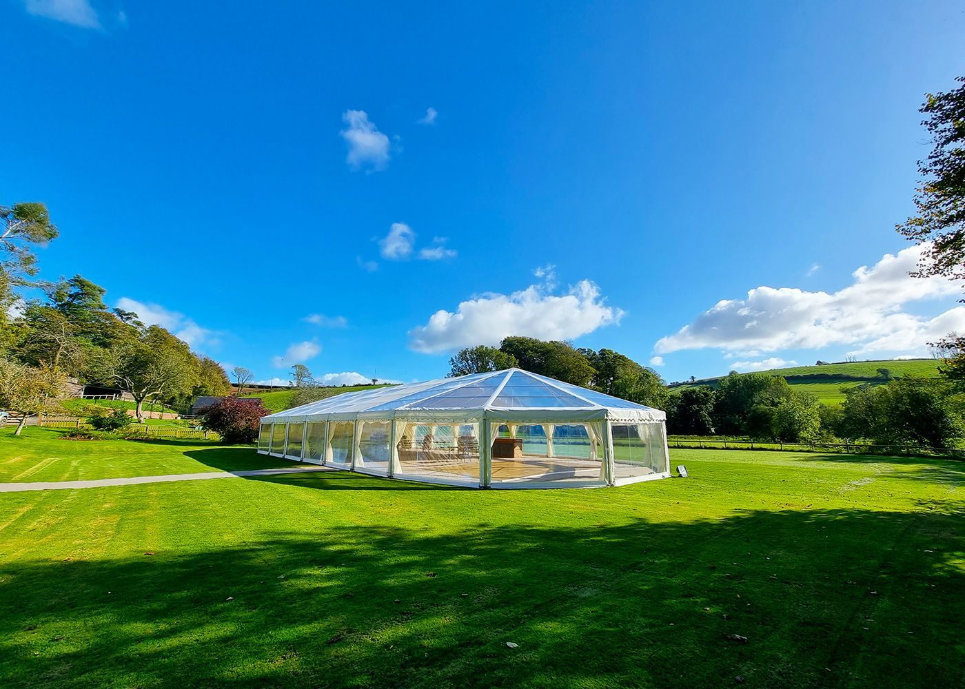 A large clear tent is sitting in the middle of a lush green field.