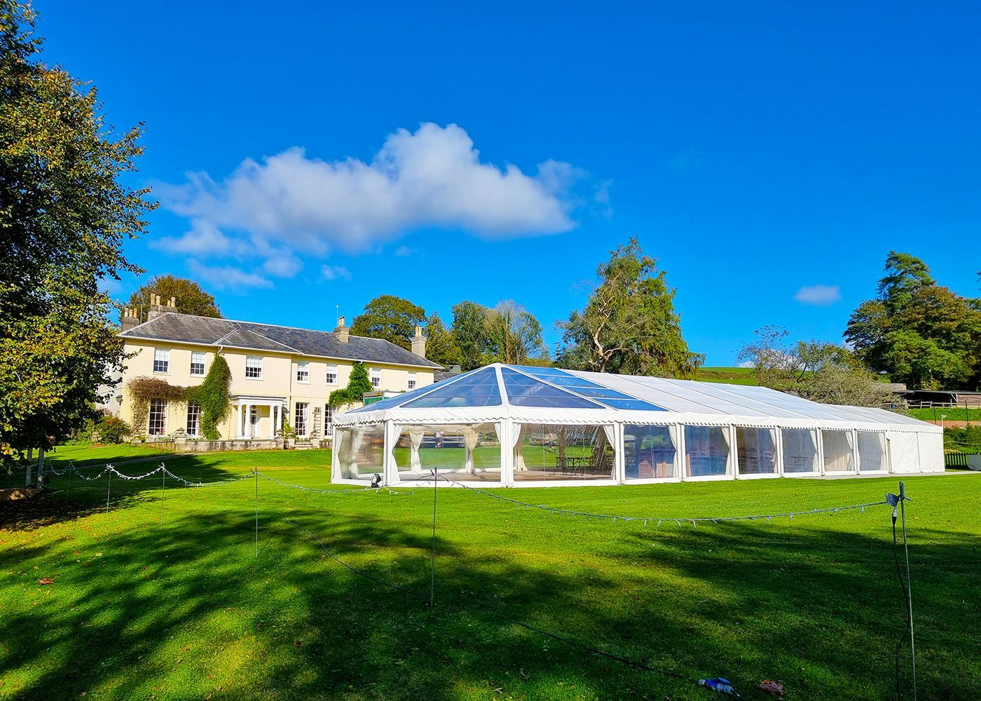 A large white tent is sitting in the middle of a lush green field.