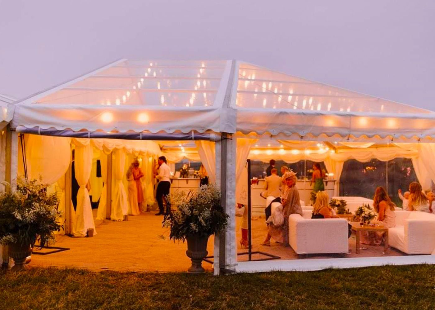 A group of people are sitting under a clear tent.