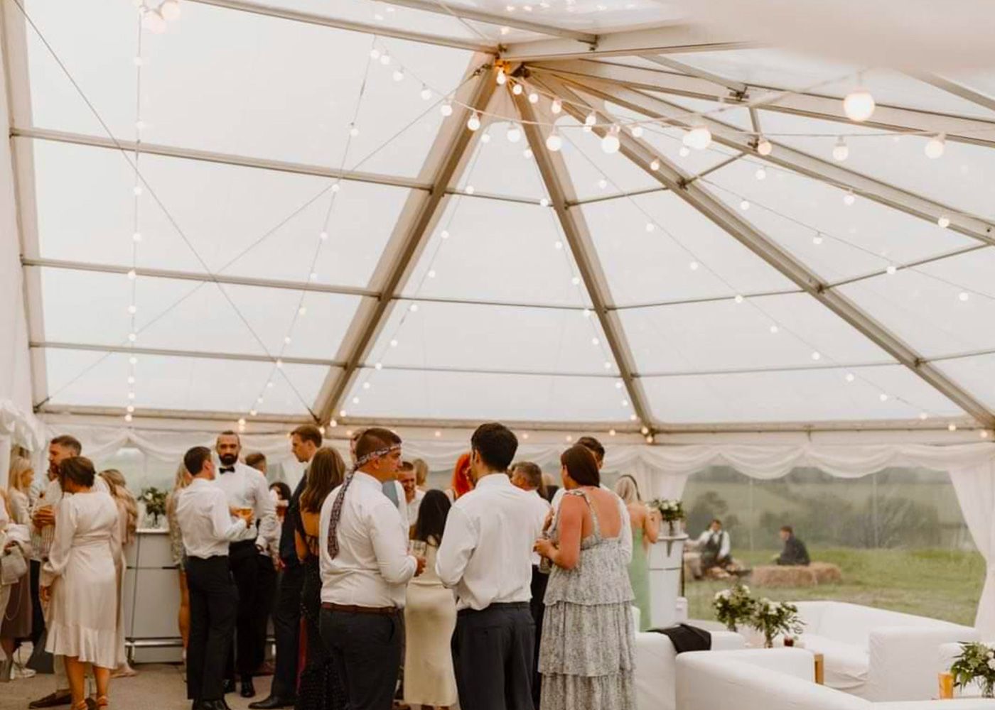 A group of people are standing under a clear tent.