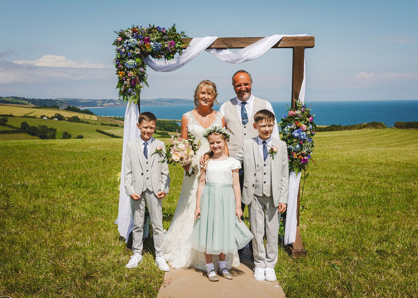 A bride and groom are posing for a picture with their children at their wedding.