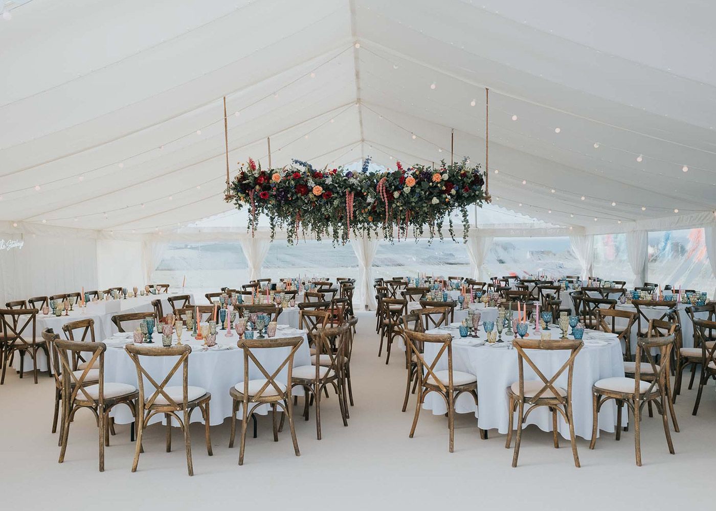 A large tent with tables and chairs set up for a wedding reception.