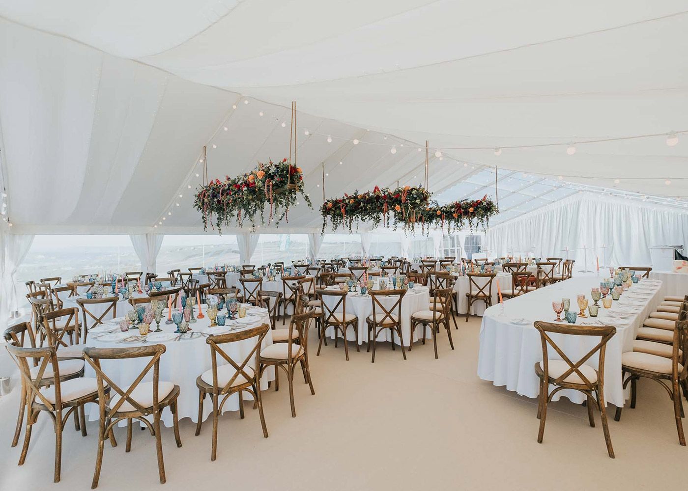 A large tent with tables and chairs set up for a wedding reception.
