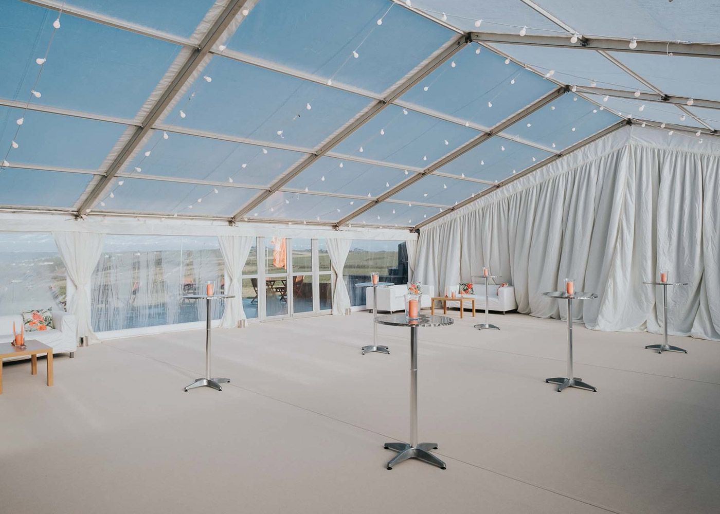 A large tent with a clear roof and tables underneath it.
