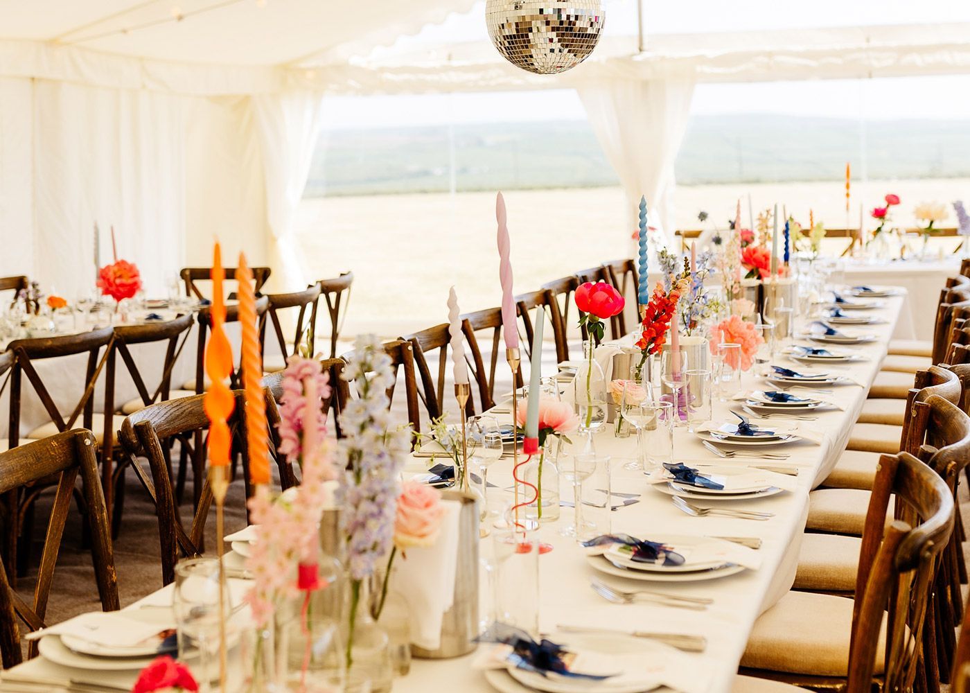 A long table is set for a wedding reception under a tent.