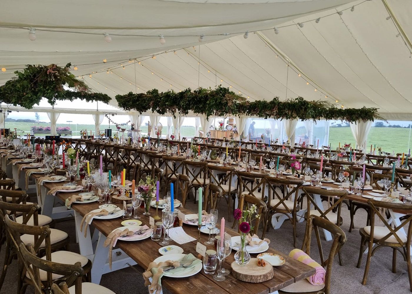 A large tent with tables and chairs set up for a wedding reception.