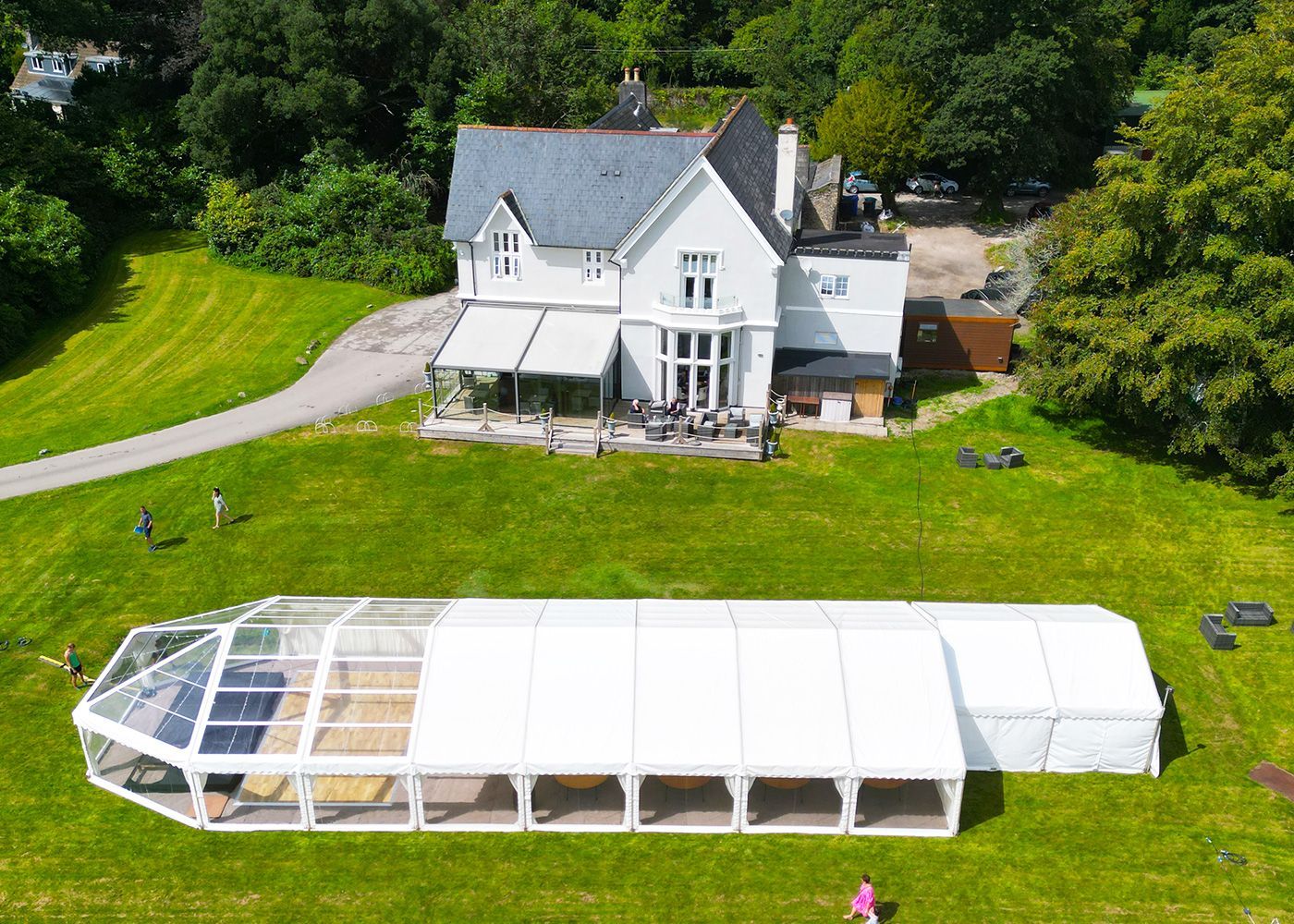An aerial view of a large white tent in front of a large house.