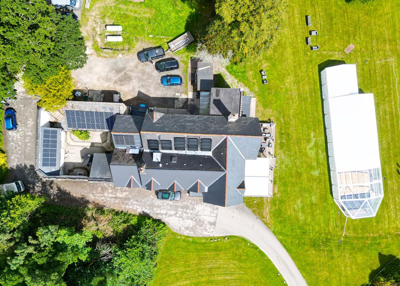 An aerial view of a large house surrounded by trees and grass.