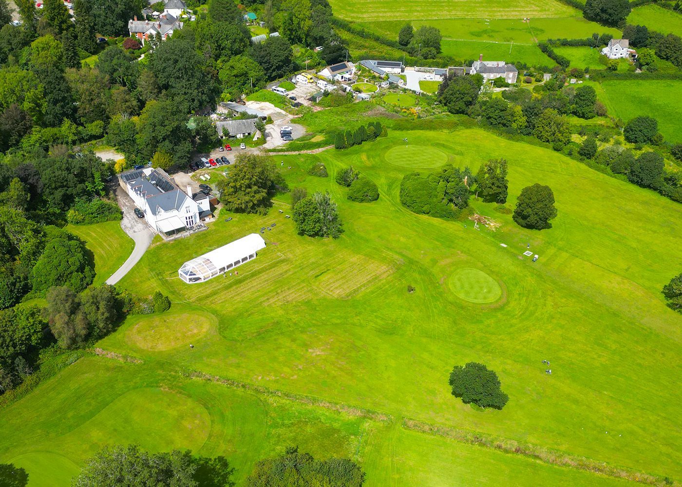 An aerial view of a golf course surrounded by trees and houses.