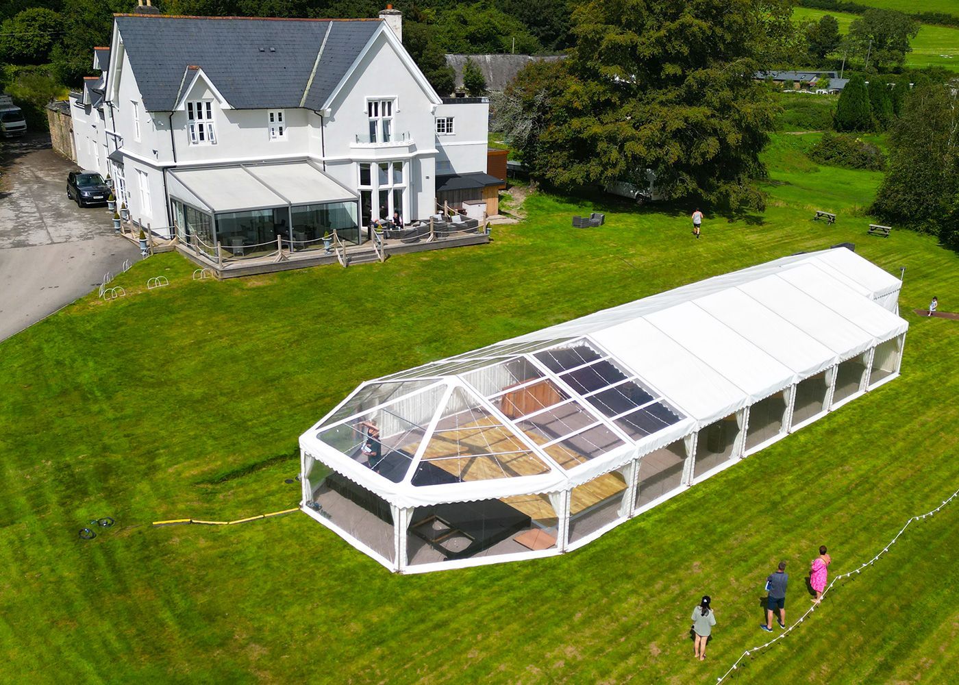 An aerial view of a large clear tent in front of a large house.