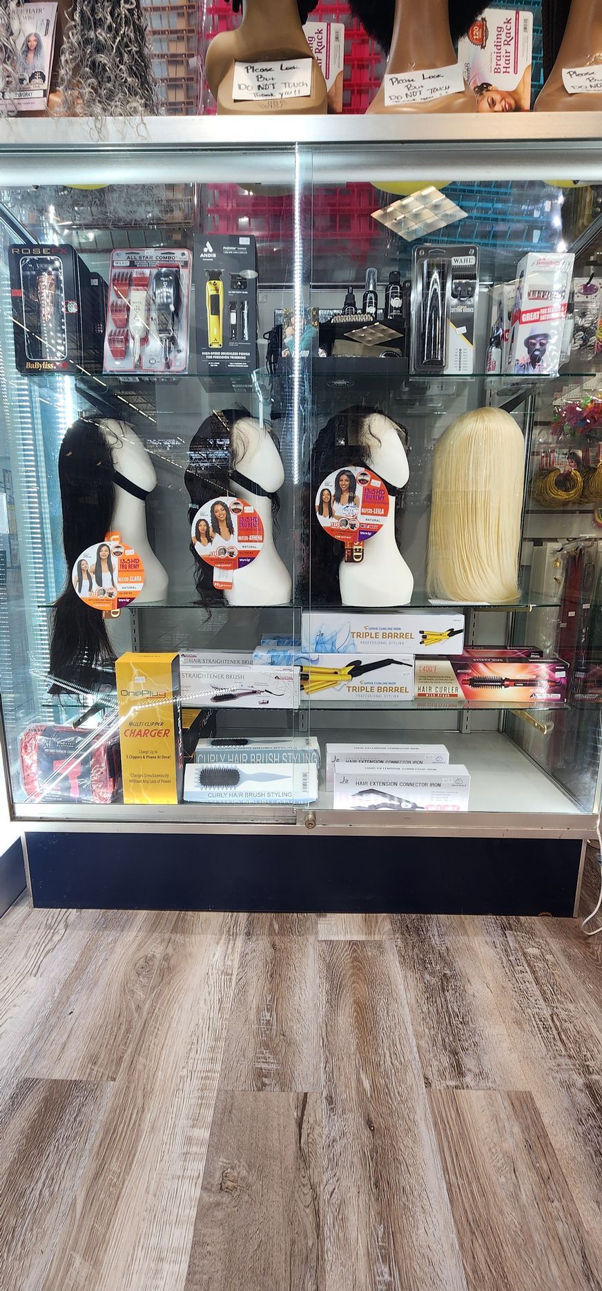 A display case in a store, filled with wigs, beauty supplies, and other products.