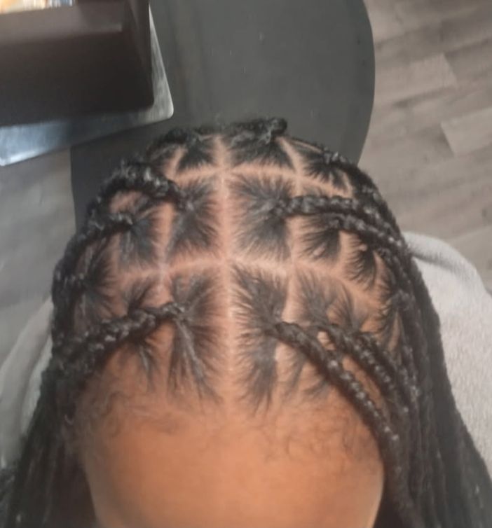 Close-up of a person's head with box braids, grid-like pattern, and neat edges.