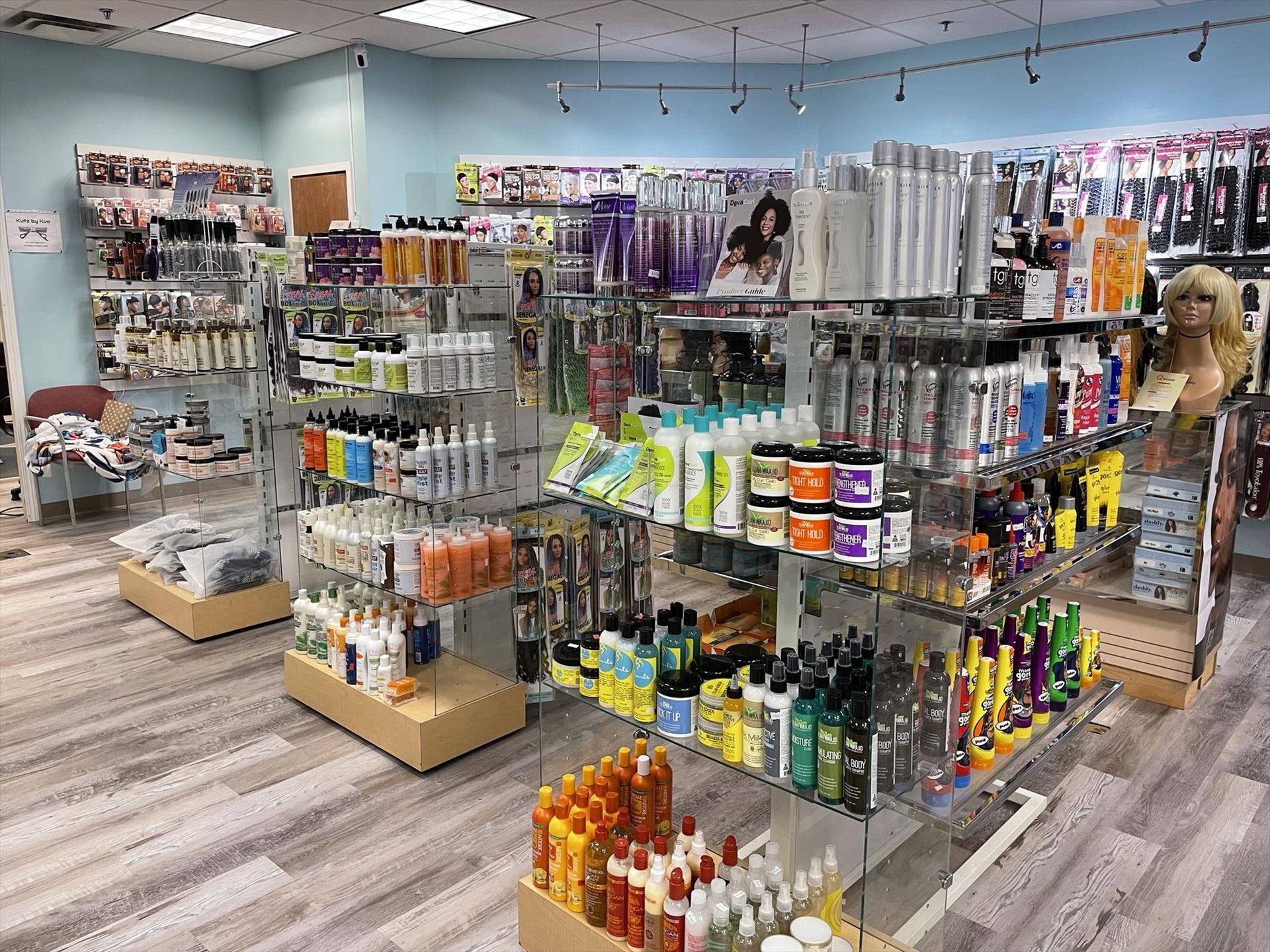 Inside a beauty supply store, shelves display hair products, extensions, and supplies.