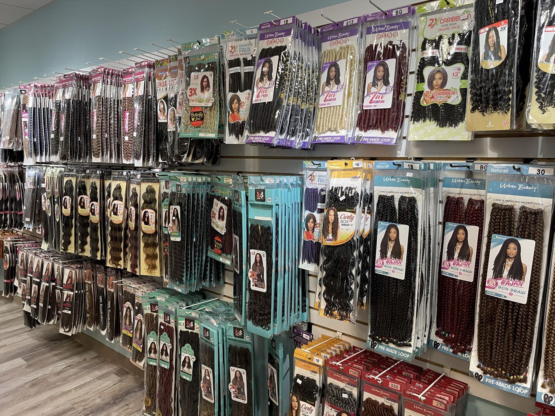 Rows of hair extensions in various colors and styles, displayed on a store wall.