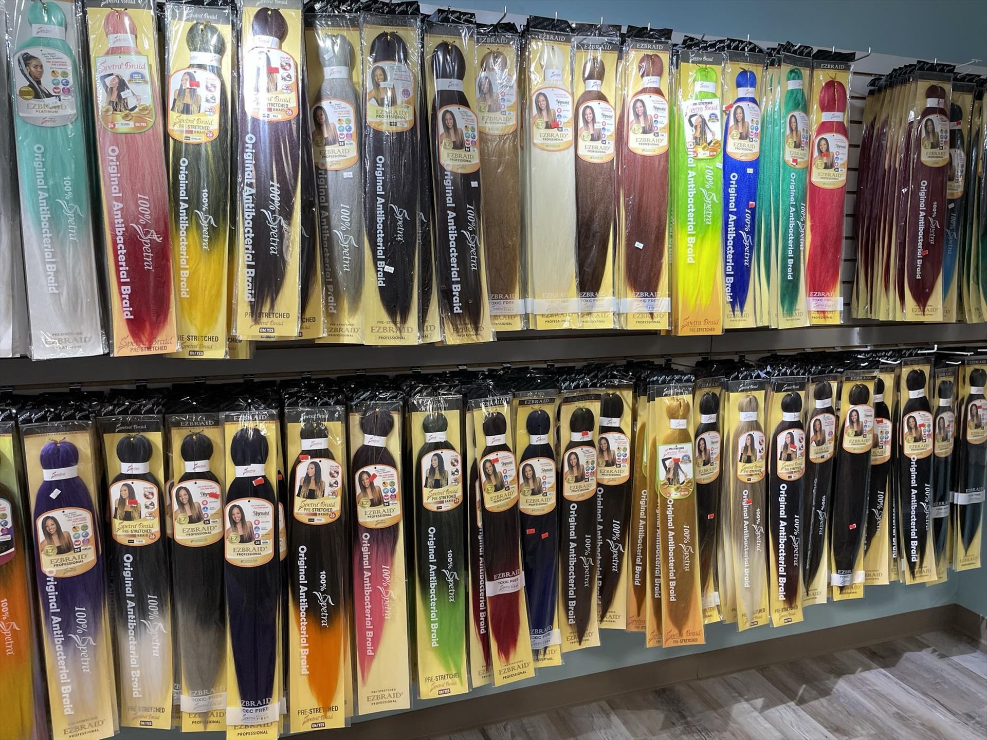 Shelves stocked with colorful braiding hair in various lengths, hues and packaged styles.