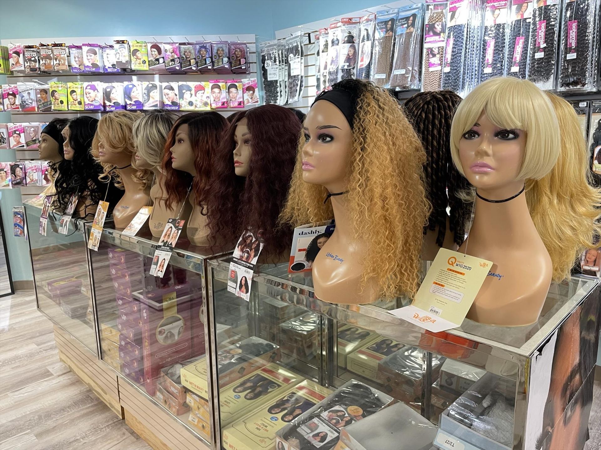 Wigs on display in a beauty supply store, including blonde, brown, and black styles on mannequins.