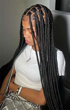 Woman with long black box braids wearing a white shirt and silver jewelry.