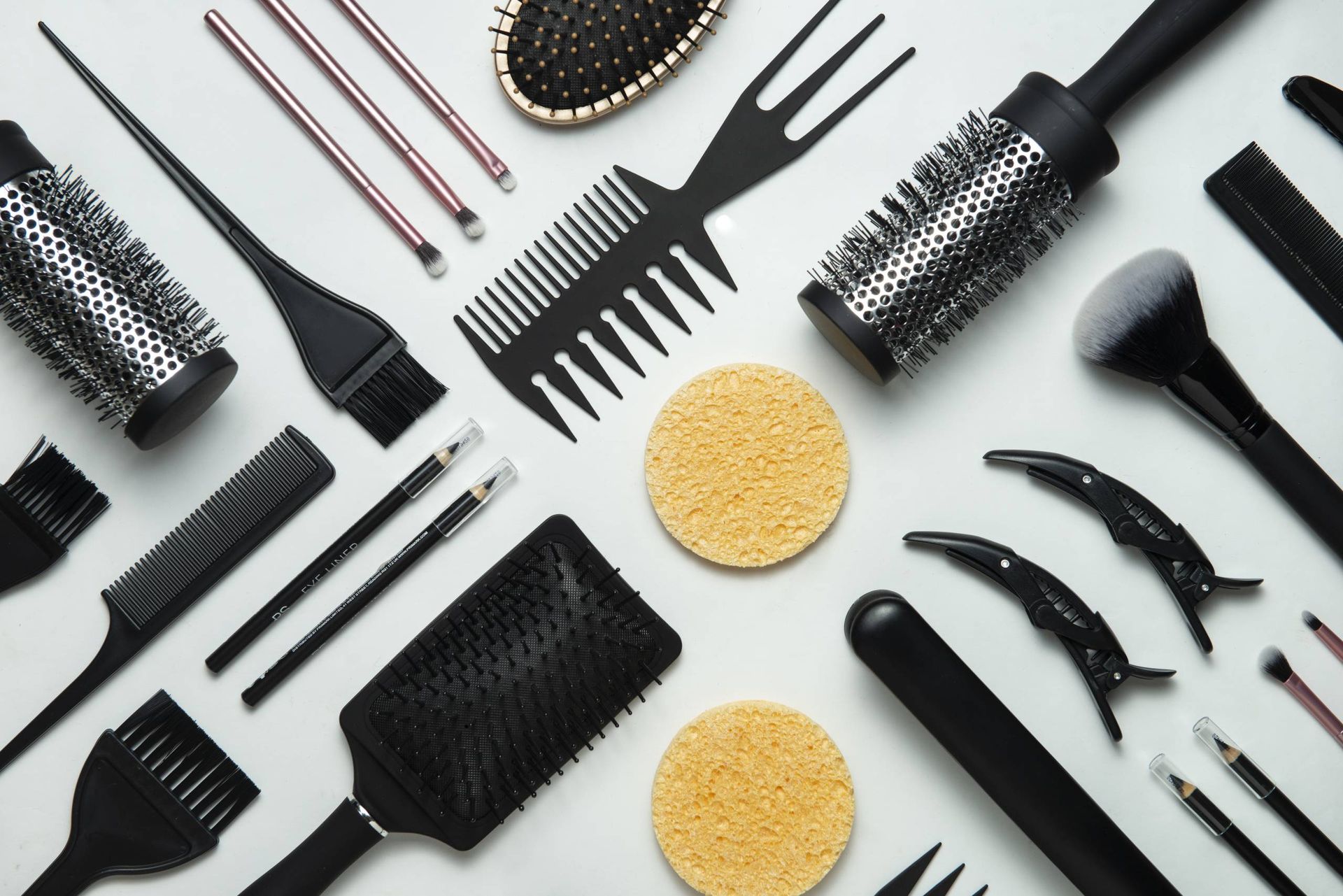 Hair styling tools arranged on a white surface, including brushes, combs, and clips.