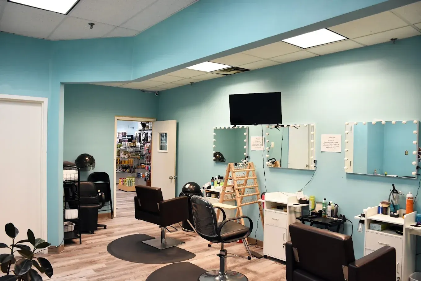 Hair salon interior: Teal walls, mirrors, styling chairs, a TV, and a doorway to another room.