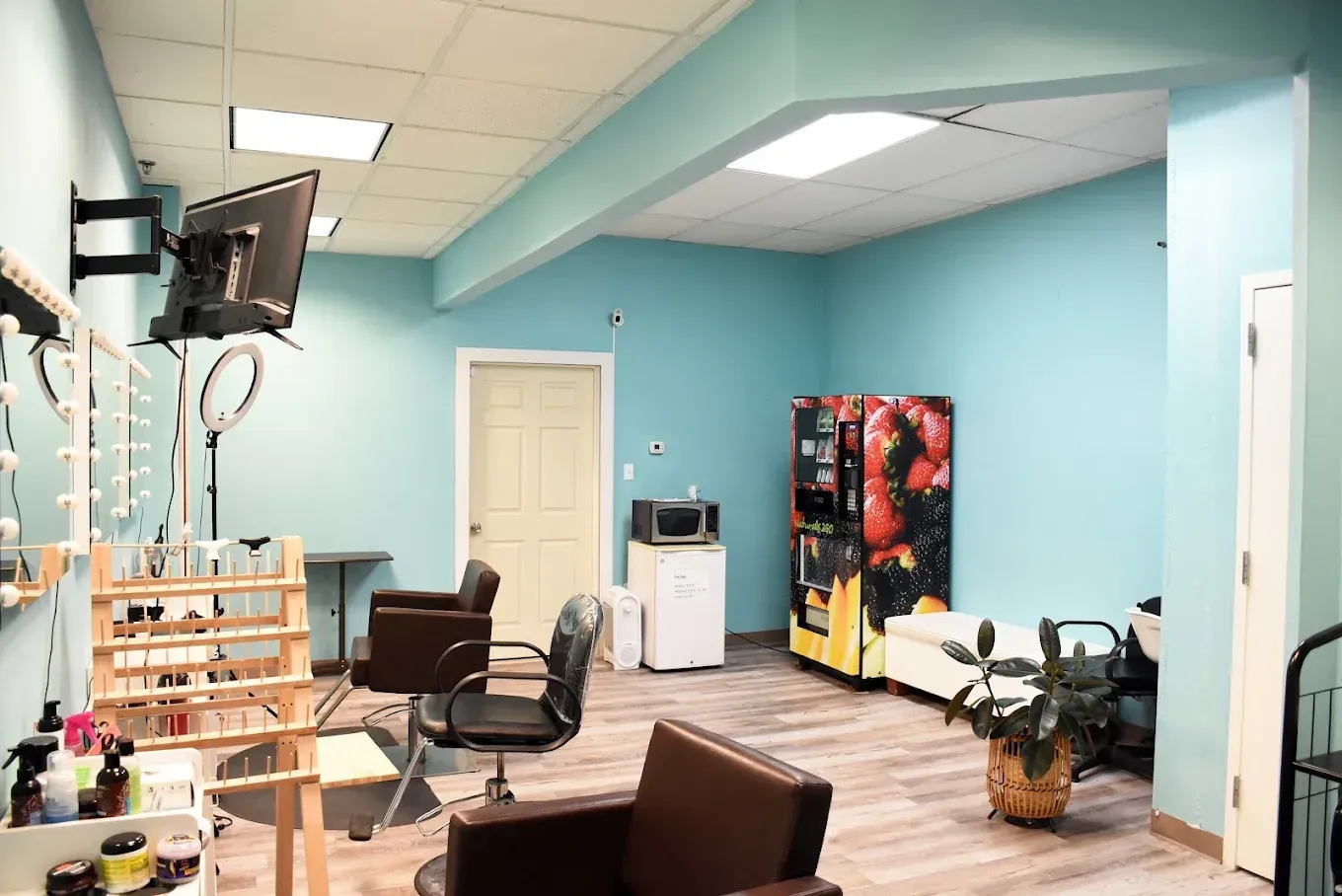 A beauty salon interior with blue walls, chairs, a vending machine, and a mirror.