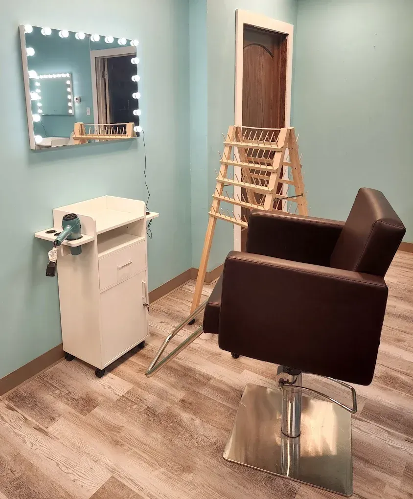 Salon interior with a brown chair, vanity mirror, and styling station.