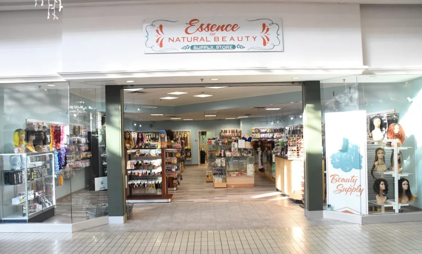 Essence Natural Beauty store in a mall. Displays wigs, hair products. Storefront with glass walls.