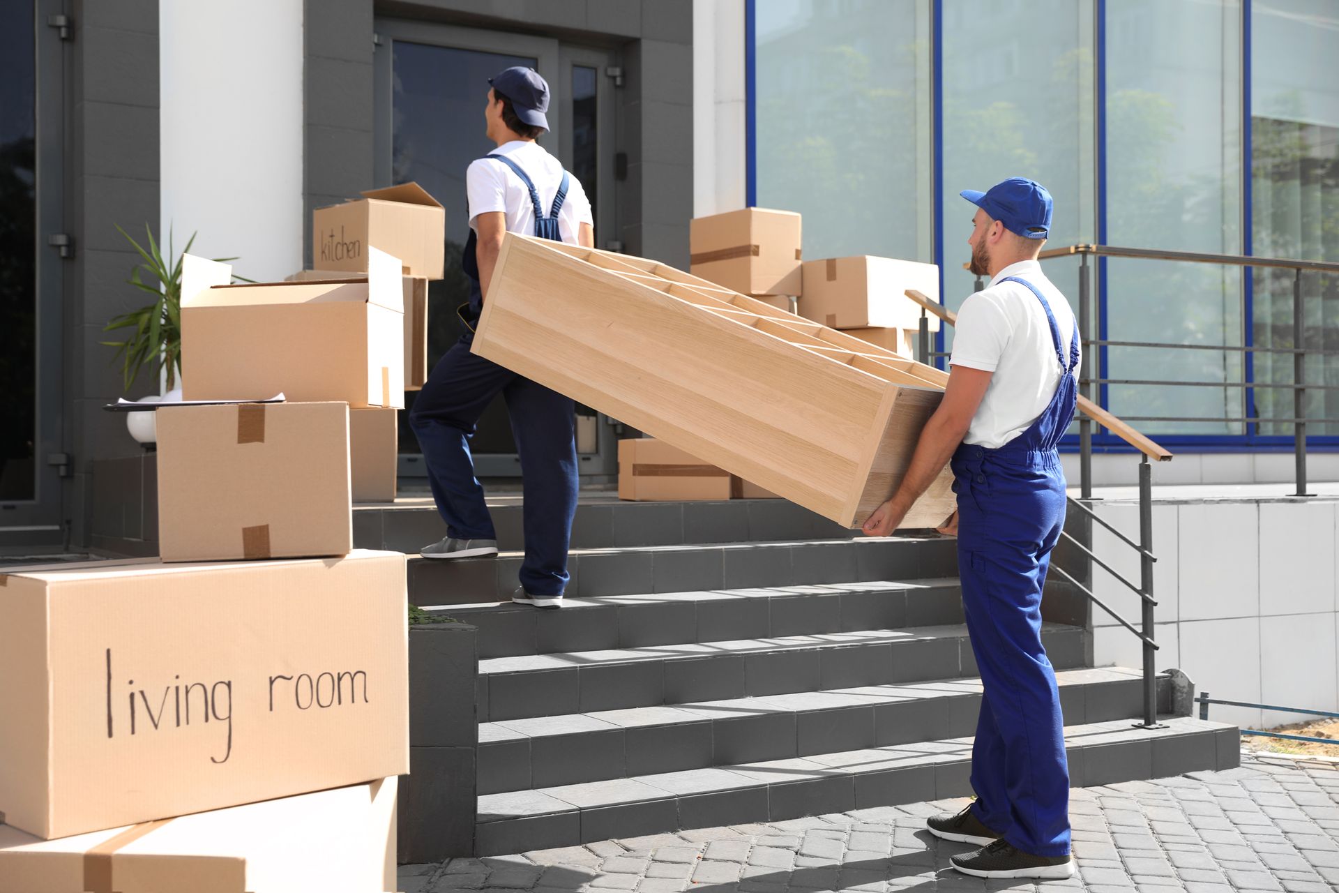 Two movers are carrying a large piece of furniture up the stairs of a building.