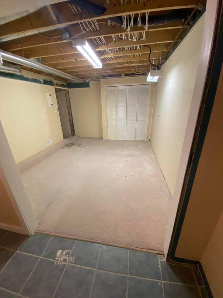 An empty basement with a tiled floor and a wooden ceiling.