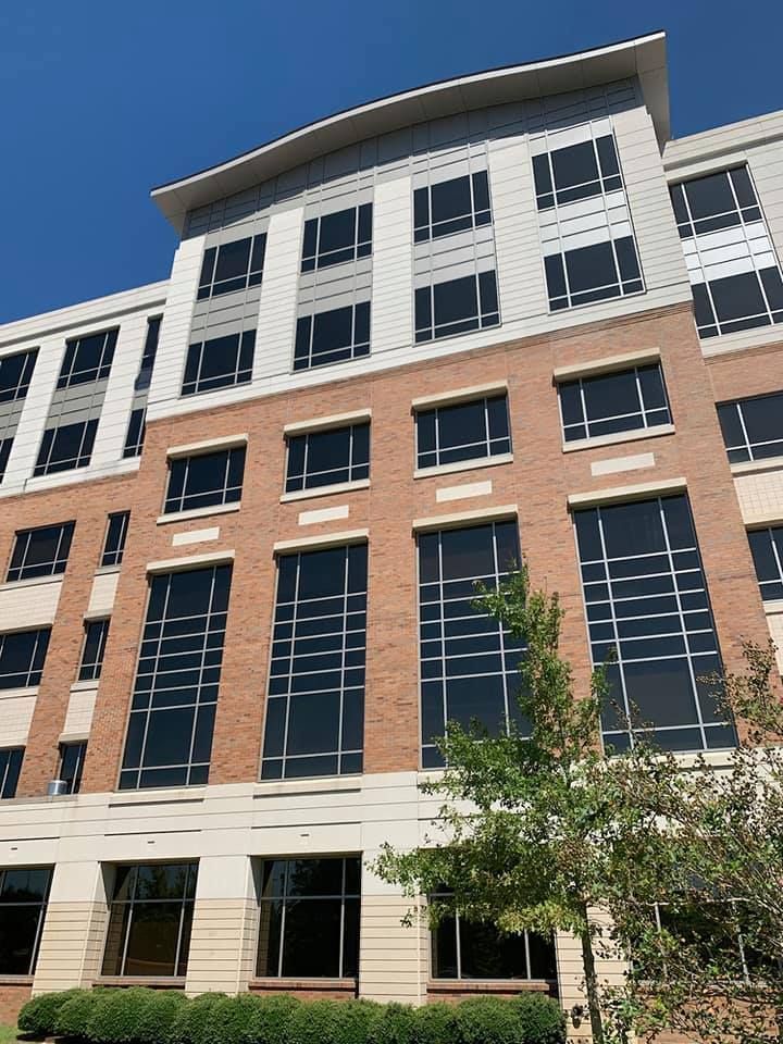 Multi-story building with brick and light gray exterior, featuring large windows and a curved roof.