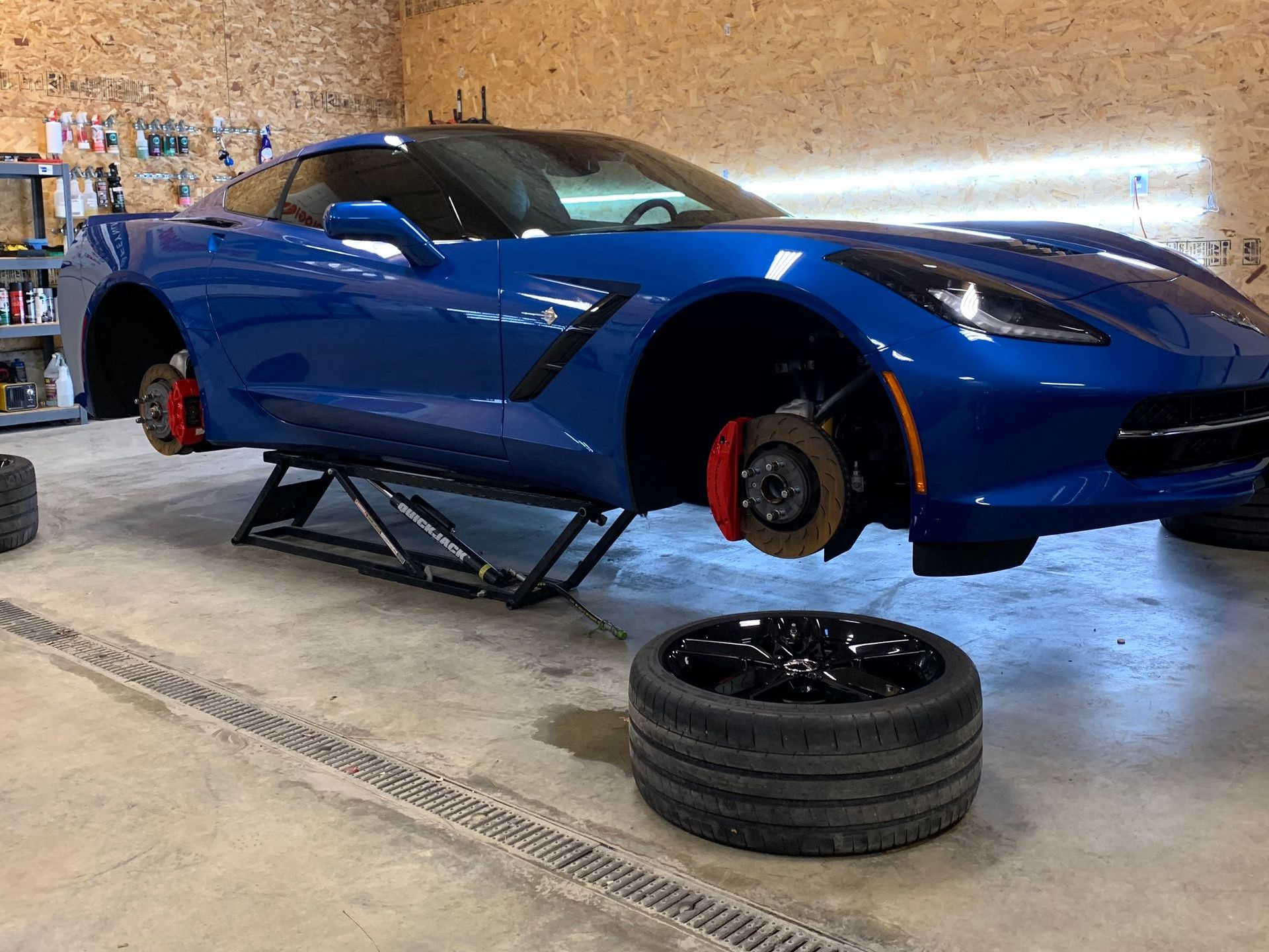A blue corvette is sitting on a lift in a garage.