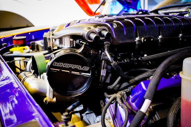 A close up of a purple car engine with the hood open.