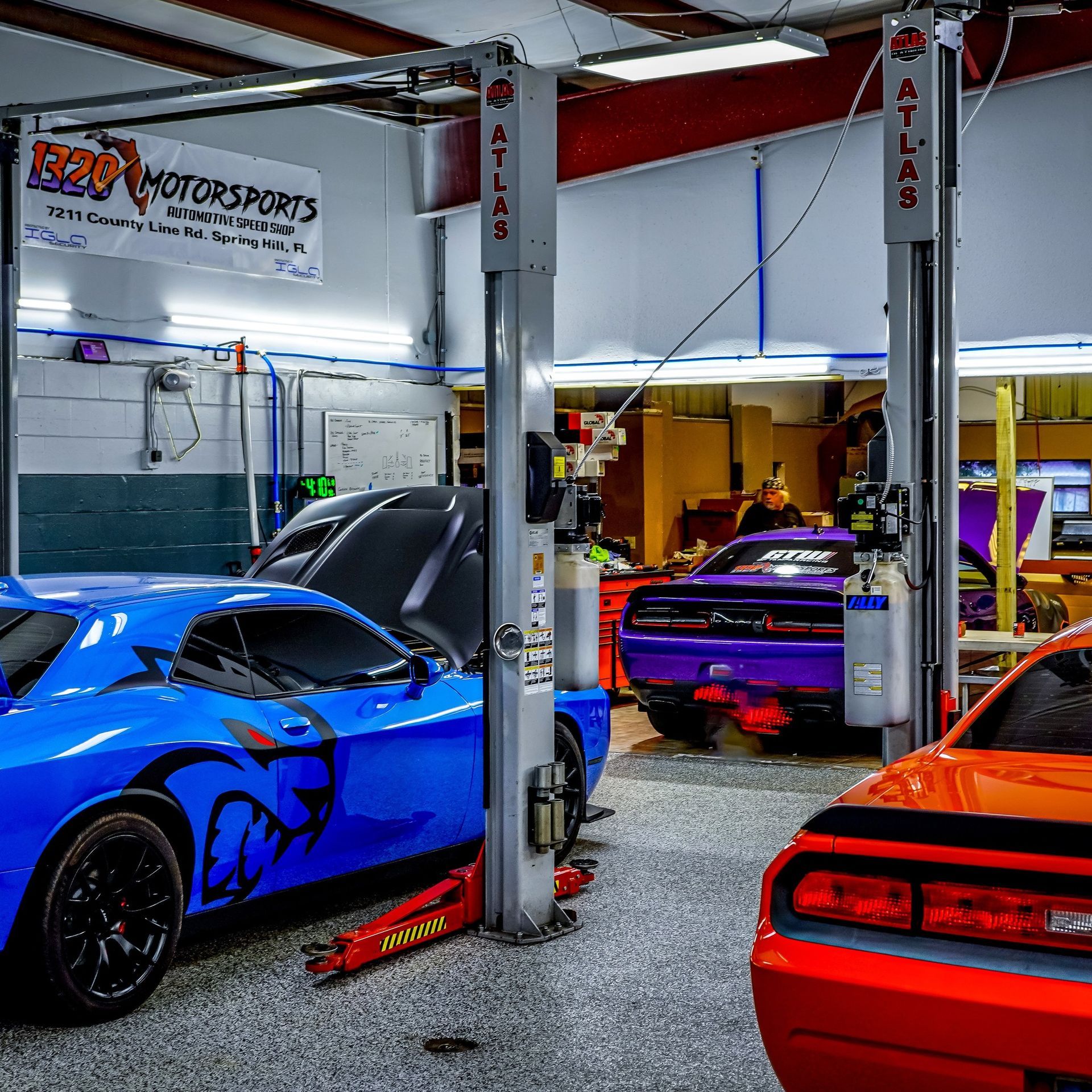 A blue car is on a lift in a garage.