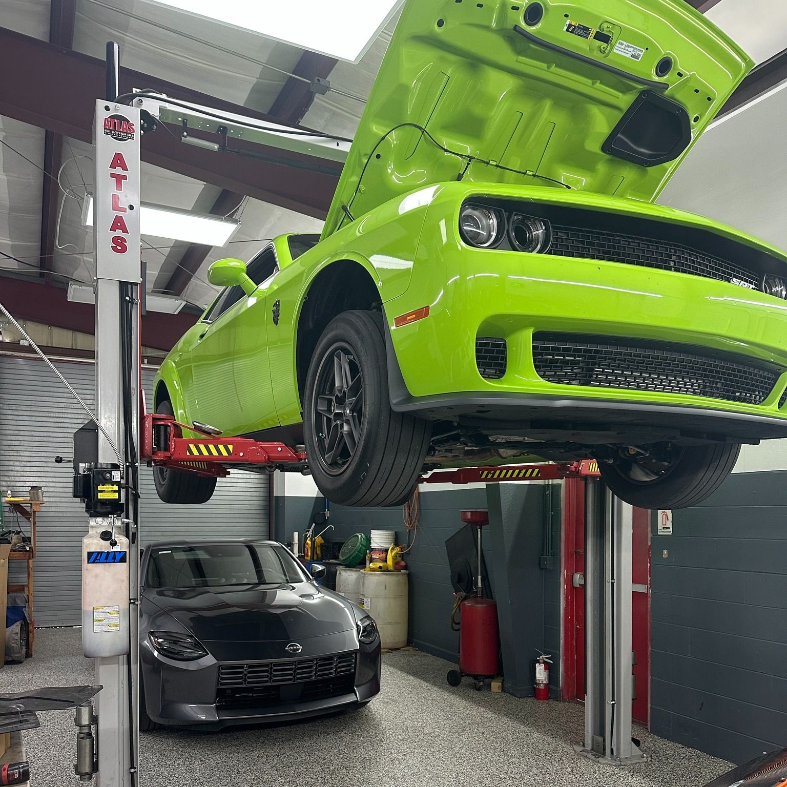 A green car is sitting on a lift in a garage.