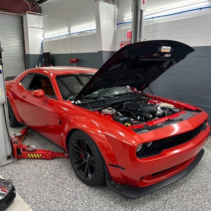 A red car with the hood up in a garage