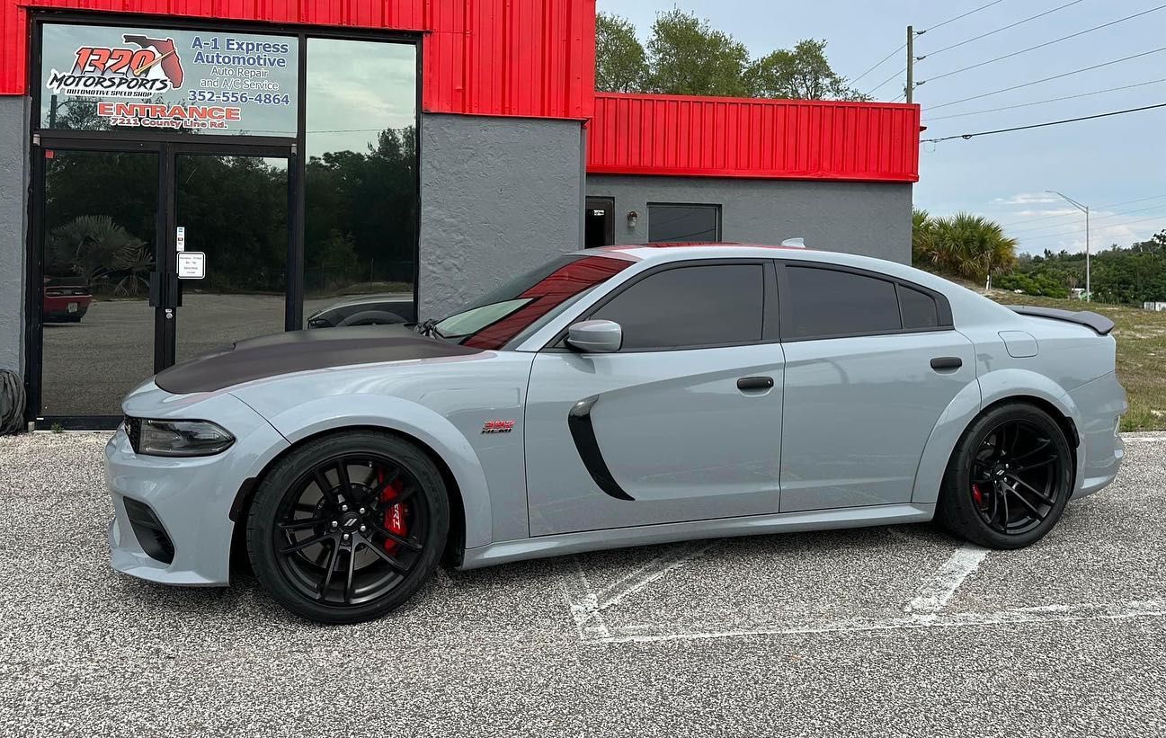 A gray dodge charger is parked in front of a building.