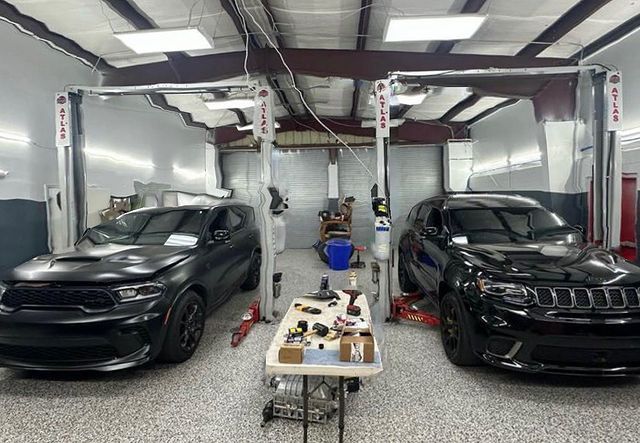 Two black cars are parked next to each other in a garage.