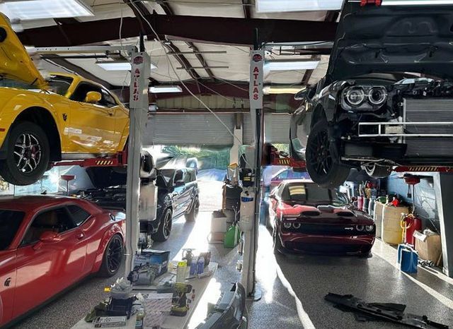 A yellow car is sitting on top of a red car in a garage.