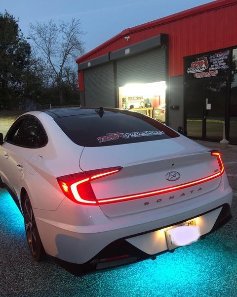 A white car is parked in front of a red building