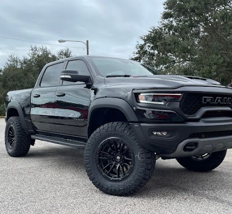 A black ram 1500 truck is parked on the side of the road.