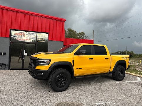 A yellow ram truck is parked in front of a red building.