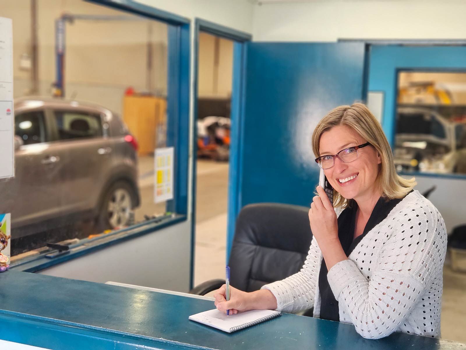Woman Sitting At A Desk Talking On A Cell Phone — Erina Car Air Conditioning In Erina, NSW