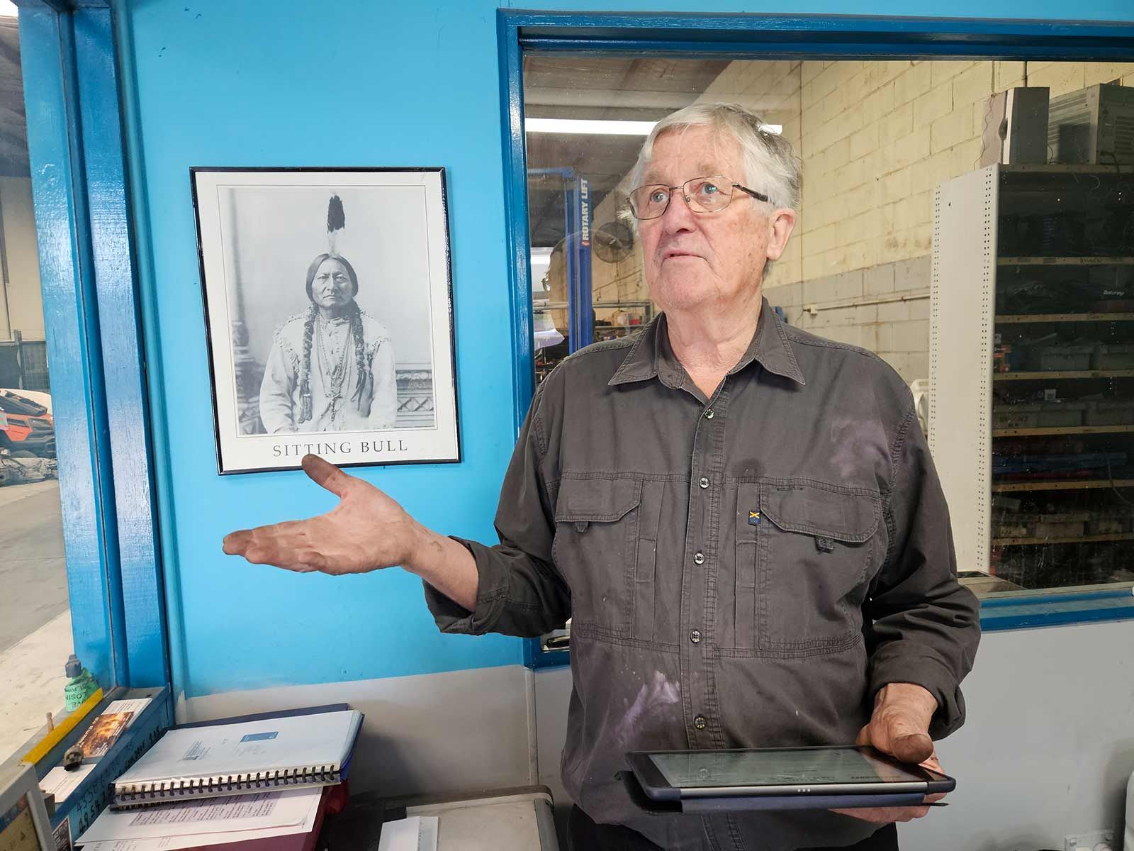 Man Standing In Front Of A Blue Wall With A Picture Of A Native American — Erina Car Air Conditioning In Erina, NSW