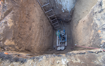 Yellow excavator loading dirt into a red dump truck, against a blue sky.
