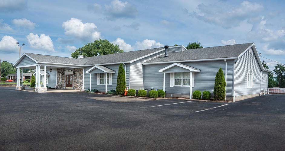 A large house with a lot of windows and a parking lot in front of it.