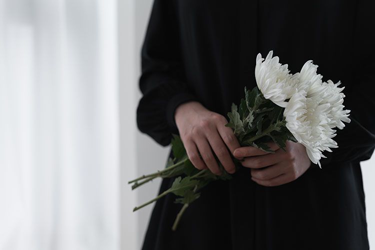 A woman in a black dress is holding a bouquet of white flowers.