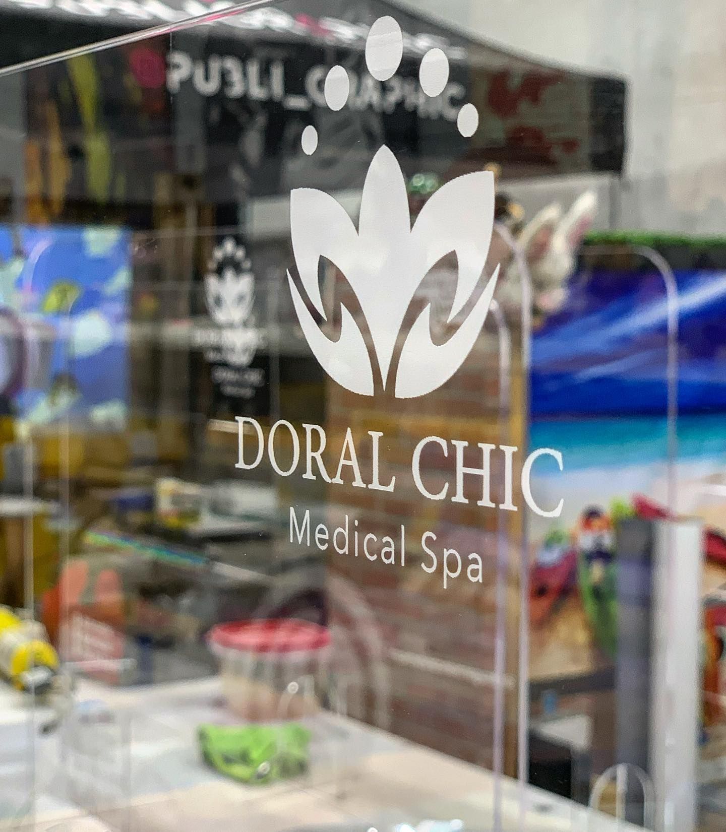 The logo for doral chic medical spa is on a glass window.