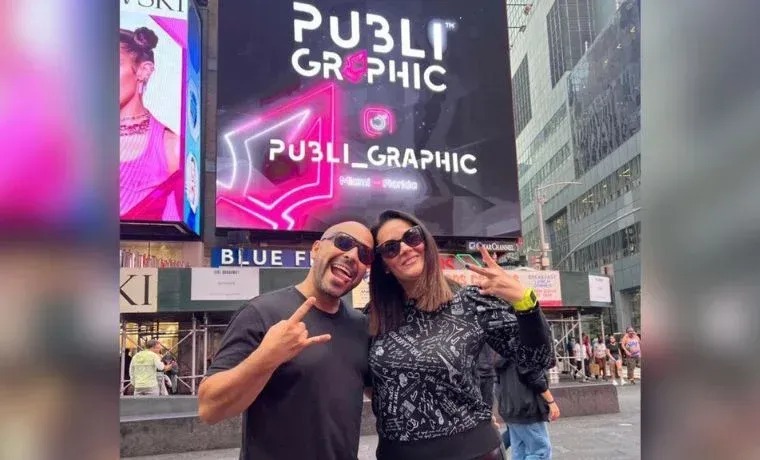 A man and a woman are standing in front of a large billboard.
